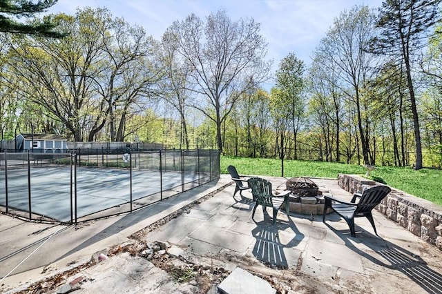view of patio with a fire pit, fence, and a tennis court