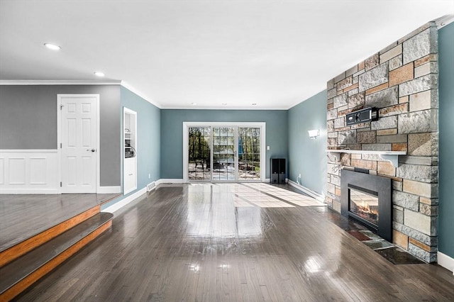 unfurnished living room featuring recessed lighting, a stone fireplace, ornamental molding, and wood finished floors