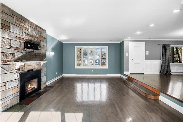 unfurnished living room with crown molding, wood finished floors, baseboard heating, and a fireplace