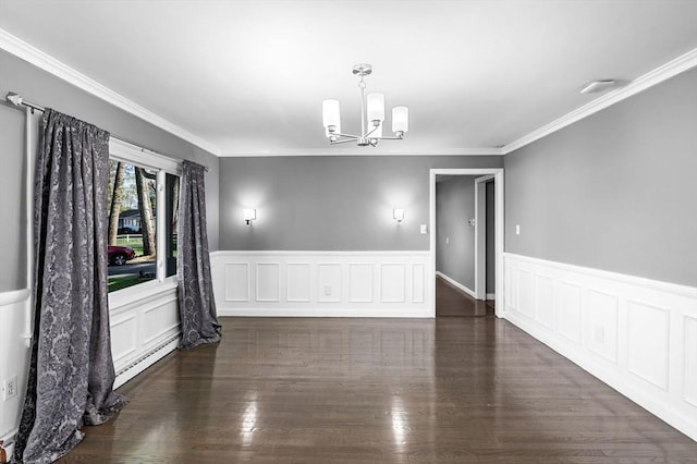 spare room featuring an inviting chandelier, ornamental molding, wainscoting, baseboard heating, and dark wood finished floors