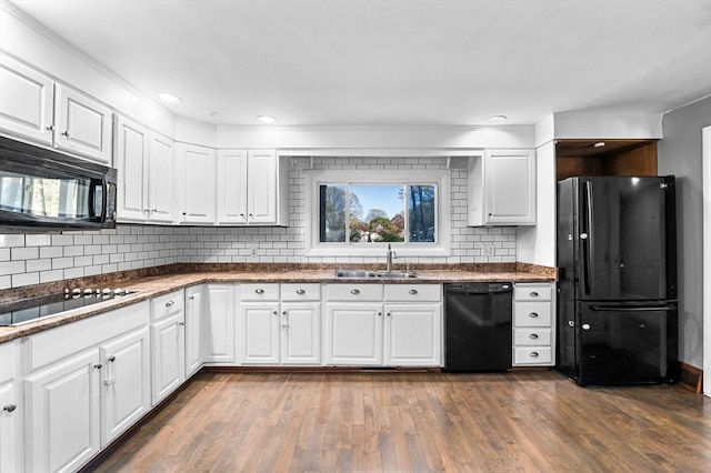 kitchen featuring decorative backsplash, dark wood-style flooring, white cabinetry, a sink, and black appliances