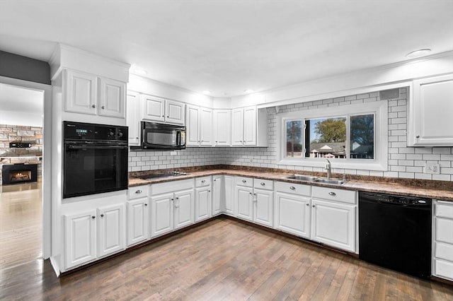 kitchen featuring backsplash, white cabinets, a sink, and black appliances