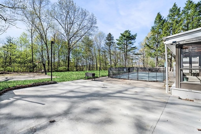 view of patio with a tennis court and fence