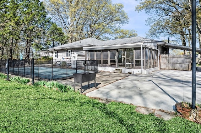 rear view of property with fence, a patio, a sunroom, a shingled roof, and a yard