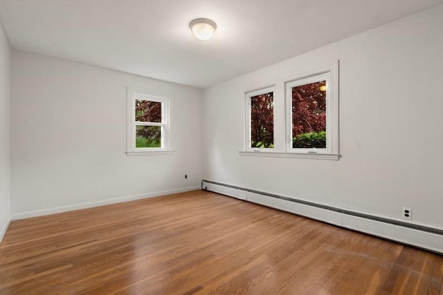 unfurnished room featuring a baseboard radiator, wood finished floors, and baseboards