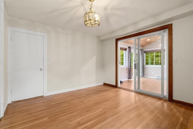 empty room featuring light wood-type flooring, a chandelier, lofted ceiling, baseboards, and baseboard heating