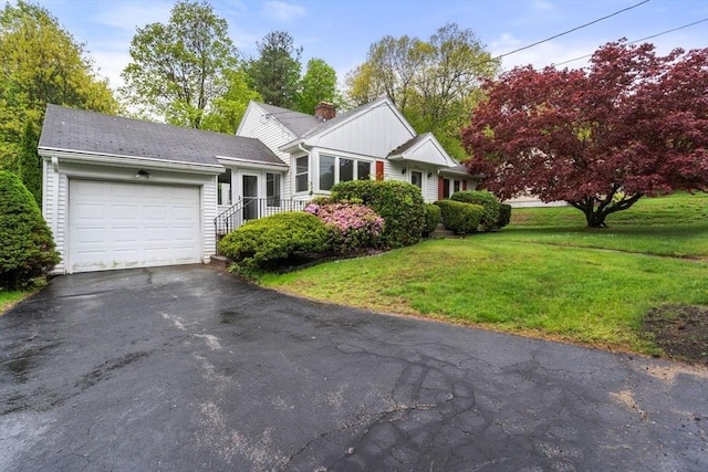 view of front of property with a garage, a front yard, driveway, and a chimney