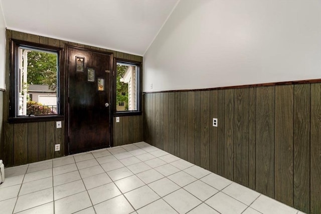 foyer with a wainscoted wall, wooden walls, and lofted ceiling