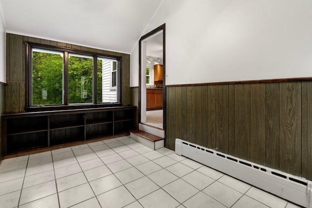 unfurnished room featuring a baseboard radiator, a wainscoted wall, light tile patterned floors, lofted ceiling, and wooden walls