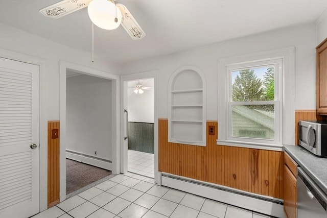spare room with a baseboard heating unit, built in shelves, and a ceiling fan