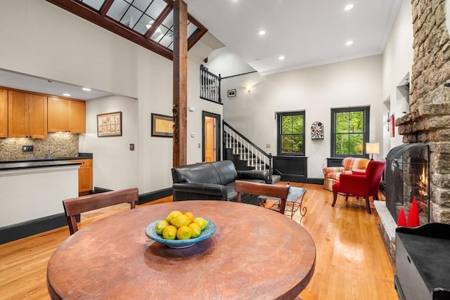 994 Centre St, Boston, MA 02130 - dining area featuring light wood finished floors, a high ceiling, a stone fireplace, recessed lighting, and stairs