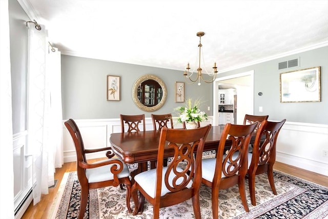 40 King Philip Dr, Rehoboth, MA 02769 - dining area featuring ornamental molding, a baseboard radiator, a wainscoted wall, light wood-style floors, and a chandelier