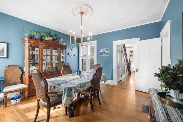 dining room featuring crown molding, light hardwood / wood-style flooring, and a notable chandelier