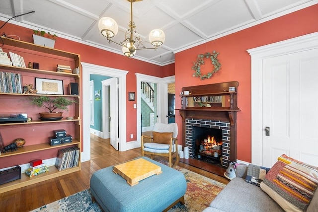 sitting room with hardwood / wood-style flooring, a brick fireplace, coffered ceiling, and a chandelier