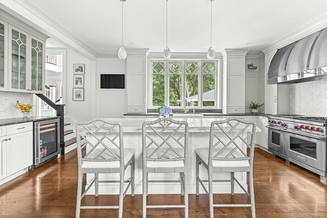 5 Stratford Rd, Winchester, MA 01890 - kitchen featuring wine cooler, range with two ovens, backsplash, wall chimney range hood, and ornamental molding