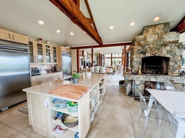 kitchen featuring sink, a stone fireplace, a center island, and built in fridge