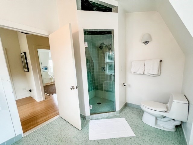 bathroom with toilet, an enclosed shower, and wood-type flooring