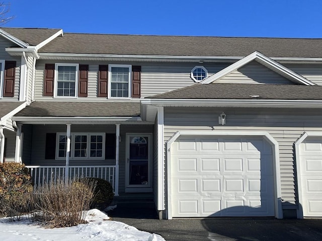 multi unit property featuring driveway, a porch, roof with shingles, and an attached garage