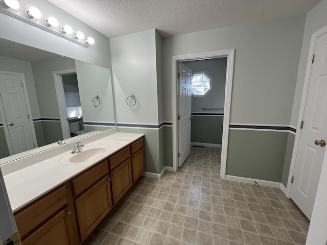 bathroom with baseboards, a textured ceiling, and vanity