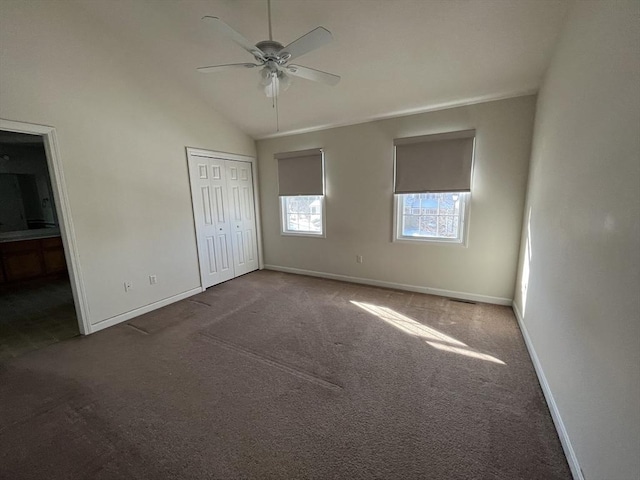 unfurnished bedroom with lofted ceiling, ensuite bathroom, baseboards, a closet, and carpet