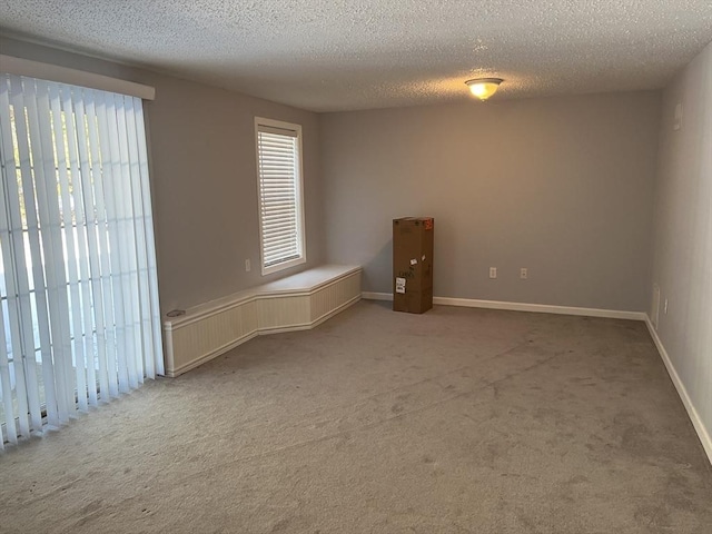 empty room featuring carpet floors, a textured ceiling, and baseboards