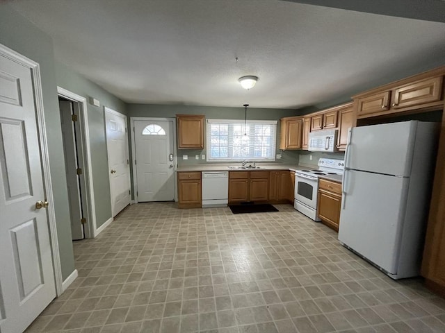 kitchen with light countertops, hanging light fixtures, a sink, white appliances, and baseboards