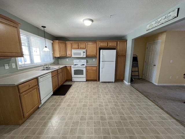 kitchen featuring white appliances, a sink, baseboards, light countertops, and pendant lighting