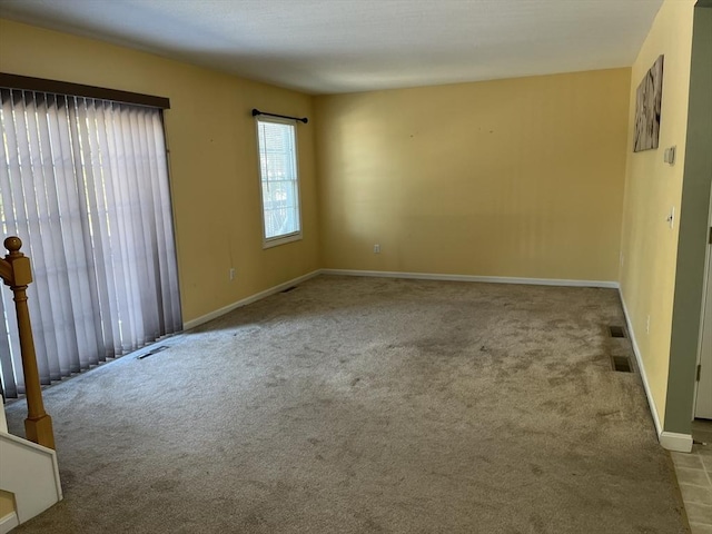 spare room with carpet floors, visible vents, and baseboards