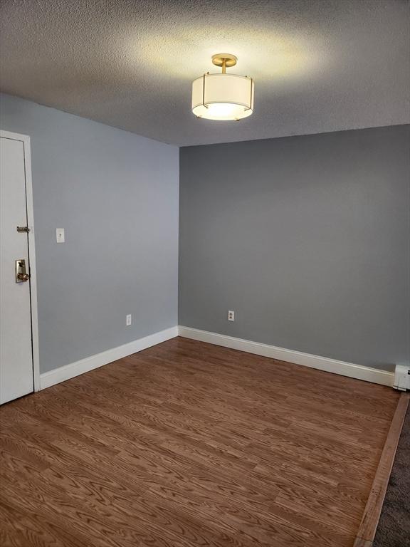 spare room featuring a textured ceiling and dark hardwood / wood-style floors