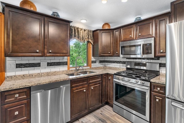 36 Tobey Rd Unit 25, Dracut, MA 01826 - kitchen with appliances with stainless steel finishes, a sink, dark brown cabinets, light wood finished floors, and light stone counters