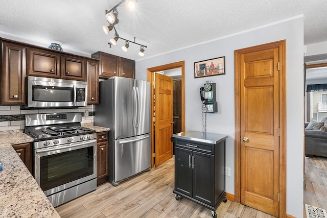 36 Tobey Rd Unit 25, Dracut, MA 01826 - kitchen with appliances with stainless steel finishes, a textured ceiling, light wood finished floors, decorative backsplash, and dark brown cabinets