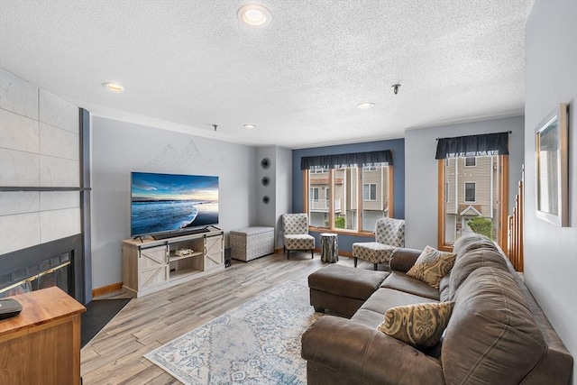 36 Tobey Rd Unit 25, Dracut, MA 01826 - living area featuring a textured ceiling, wood finished floors, a tiled fireplace, recessed lighting, and baseboards