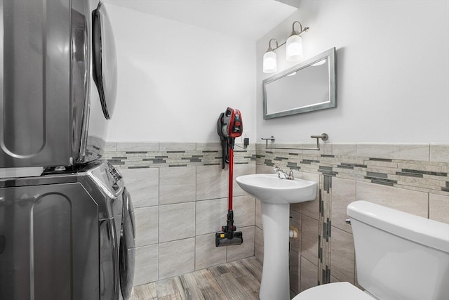 36 Tobey Rd Unit 25, Dracut, MA 01826 - bathroom featuring estacked washer and dryer, tile walls, toilet, wainscoting, and a sink