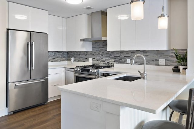 121 Portland St Unit 902, Boston, MA 02114 - kitchen featuring appliances with stainless steel finishes, wall chimney exhaust hood, a peninsula, dark wood-type flooring, and white cabinetry