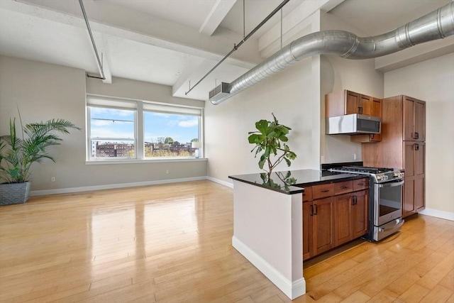 51 Lafayette St Unit 304, Salem, MA 01970 - kitchen with gas range, light wood-style flooring, dark countertops, white microwave, and brown cabinets