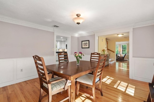 48 Pine Hill Dr, Walpole, MA 02081 - dining space with light wood finished floors, crown molding, a wainscoted wall, and a decorative wall