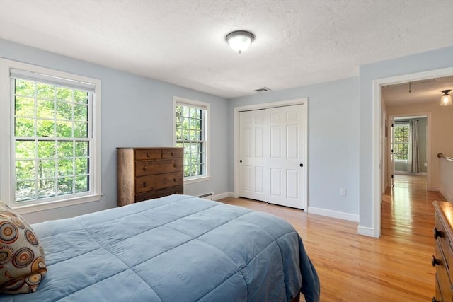 48 Pine Hill Dr, Walpole, MA 02081 - bedroom with light wood-type flooring, baseboards, a textured ceiling, a baseboard radiator, and a closet