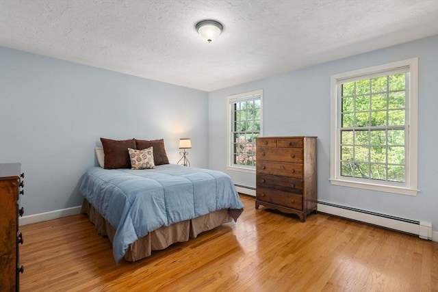 48 Pine Hill Dr, Walpole, MA 02081 - bedroom with baseboard heating, light wood-type flooring, baseboards, and a textured ceiling