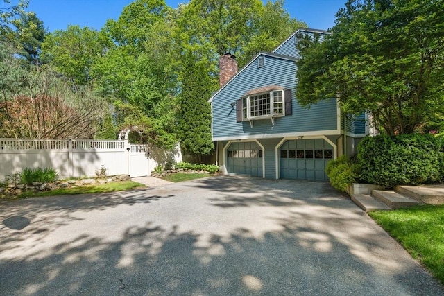 48 Pine Hill Dr, Walpole, MA 02081 - view of home's exterior featuring driveway, a chimney, an attached garage, and fence
