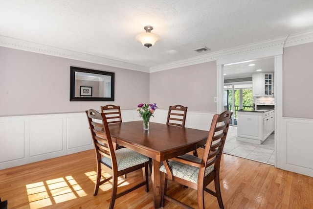48 Pine Hill Dr, Walpole, MA 02081 - dining space featuring ornamental molding, light wood-type flooring, wainscoting, and a decorative wall