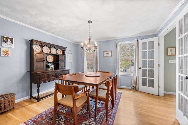 dining space with a chandelier, light wood-style floors, french doors, ornamental molding, and baseboards