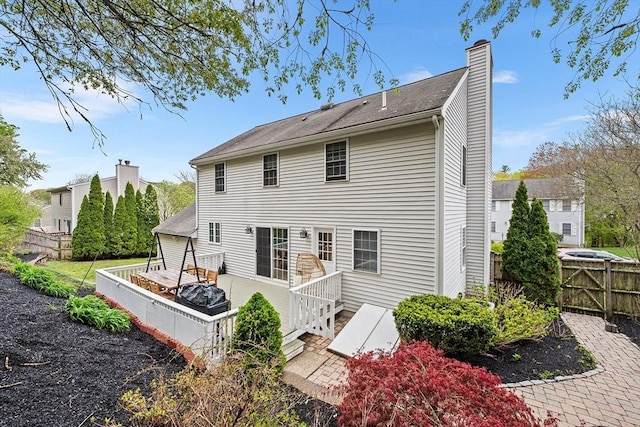 rear view of property featuring fence and a chimney
