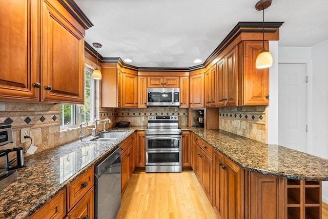 kitchen featuring stainless steel appliances, a sink, light wood-style flooring, brown cabinetry, and recessed lighting