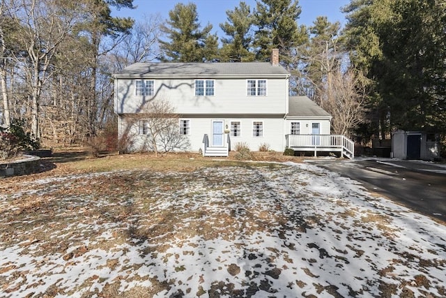 snow covered back of property featuring a wooden deck