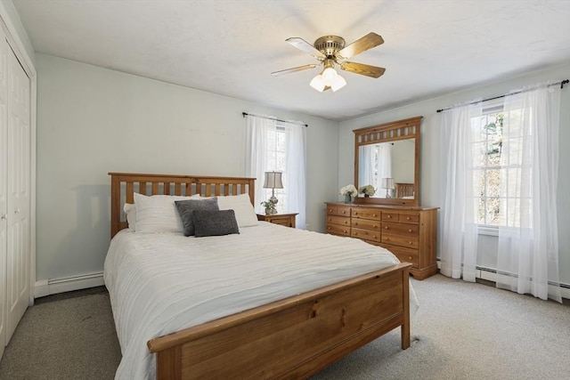 carpeted bedroom with ceiling fan, multiple windows, a baseboard heating unit, and a closet