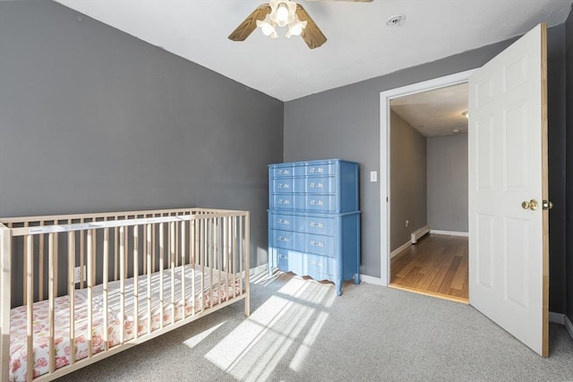 unfurnished bedroom featuring ceiling fan, carpet, and a crib