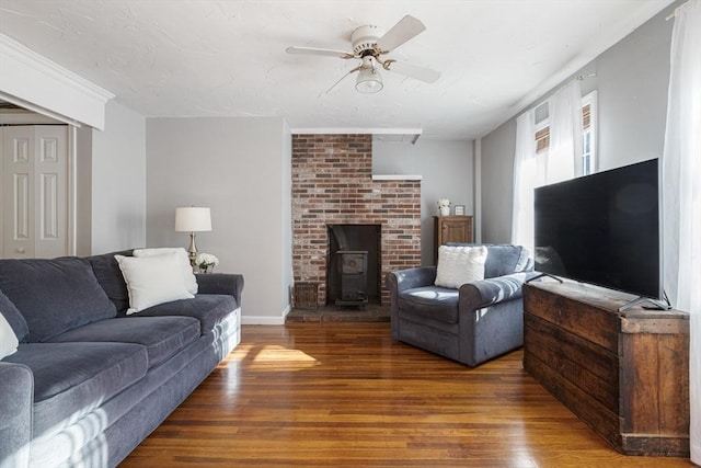 living room featuring ceiling fan, a wood stove, and dark hardwood / wood-style flooring