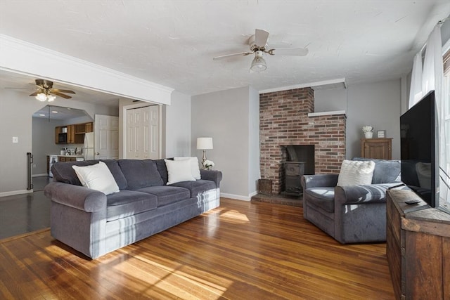 living room with ceiling fan, a wood stove, and dark hardwood / wood-style floors