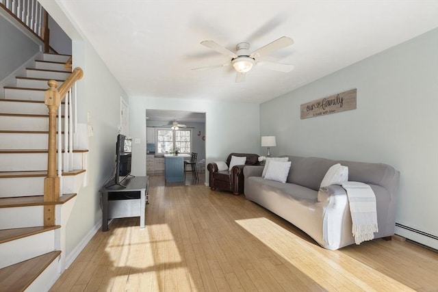 living room with ceiling fan, a baseboard heating unit, and light hardwood / wood-style flooring