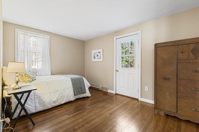 bedroom with baseboard heating and dark hardwood / wood-style floors